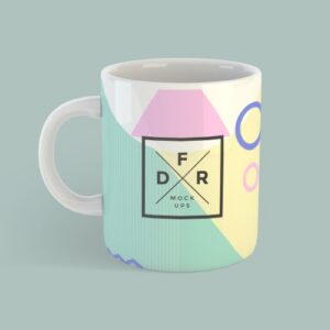 Ceramic mug featuring a pastel geometric design with a black square logo at the center, containing diagonal lines and letters, on a muted teal background.